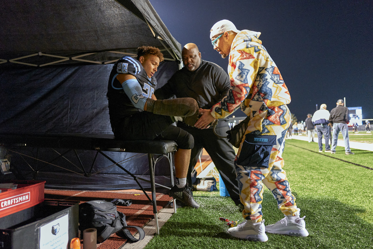 Off the field and between tackles, Thomas gets encouragement—and adjustments on his “athletic leg”—from Devon and Josh.